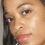 Close-up of a person's face with light skin tone, dark eyebrows, and pink lips; partial view shows black hair on the left side.