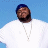 Pixelated static image of a person wearing white clothing and a silver chain against a blue background.