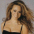 Static pixelated image of a woman with long wavy brown hair wearing a black spaghetti-strap top against a light gray background.
