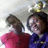 Two people in red and purple shirts pose with a trophy on the head, one person's arm moves from raised to lowered position.
