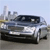 Pixelated image of a silver car with dark windows and a black roof, positioned on a light gray surface under a pale blue sky.