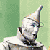Pixelated figure with white and gray tones, wearing a tall pointed hat, seated against a green background with a vertical light green stripe.