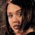 Pixelated close-up of a person's face with dark hair against a blurred background, showing partial facial features and skin tones.