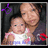 Static pixelated image of two people in close pose, one holding a child-like figure with light brown hair wearing white and pink clothing against dark background.