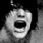 Pixelated grayscale image of a stylized face with wide eyes and an open mouth, set against a dark background with a light gradient on the right.