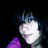 A person with dark hair and bangs wears a purple top against a black background, with visible pixelation and motion blur