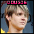 A pixelated image of a person with light brown hair wearing a yellow shirt, displayed in two side-by-side under the text 'DOUGIE' at the top