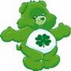 Green cartoon bear with white chest patch featuring a four-leaf clover, arms outstretched, standing against a plain white background.