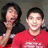 Two people in a pixelated photo with red text overlays on a black background, one person in red shirt smiling, the other covering mouth.