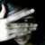 A person with dark hair covers their face with a hand, revealing eyes and mouth in with slight hand movement