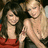 Two women in red dresses pose together, one with long dark hair and the other with blonde hair styled up.