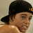 A pixelated image split into two sections: a person wearing a black cap with a yellow emblem on the left, and a bright pink background with black text on the right.