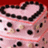 Pixelated pink cake with black polka dots and a heart-shaped chocolate border on red background, next to text 'i LOVE DAVID <3 !!' in pixel font.