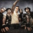 Pixelated image of a group with one central figure holding a sword, surrounded by others in dynamic poses against a dark background.
