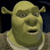 Pixelated green ogre with large ears, wide eyes, and open mouth against dark background, wearing light-colored shirt.