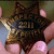 A star-shaped icon with a textured brown and gold pattern held by fingers, displaying the word "FELL" in dark letters across its center.