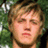 Pixelated close-up of a person with light brown hair and closed eyes against a green foliage background.