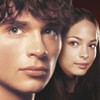 Two people with light skin tones appear in close-up, facing forward with neutral expressions against a dark background.