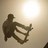 Pixelated silhouette of a figure holding an object against a bright light source background.