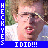 Pixelated image of a person with light brown hair and glasses, wearing a white shirt against green foliage background, framed by blue borders with text.