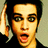 Pixelated close-up of a person with dark hair, light skin, and green eyes making an exaggerated open-mouth expression while raising their right hand near the head.
