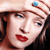 A pixelated close-up of a person with light skin, dark brown hair, and red lips wearing a light-colored headband with a blue gem.