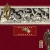 Pixelated image with red background, central gray banner containing black and white text-like shapes, and a small red rectangular element below.