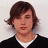 Pixelated portrait of a person with brown hair, wearing dark clothing over a white collar against light background.