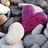 A static pixelated image shows a figure in white clothing holding a large purple heart-shaped object against a blurred background.