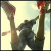 A person in dark clothing and red sneakers is captured mid-air with legs spread wide against a bright sky background.