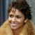 A pixelated close-up of a person with short brown hair wearing a light brown garment against a blurred background.