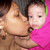 A pixelated image shows a person kissing another person's cheek; the second person wears a bright pink top with green trim.