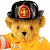 Pixelated teddy bear in orange firefighter gear with black helmet featuring red and gold emblem, standing against white background.