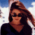 A pixelated image of a person with long brown hair wearing dark sunglasses and a black top, positioned next to green text reading 'Original Icons .com' on a solid background.