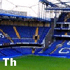 A stadium with blue seats and white lettering, showing partial text overlays on green grass sections.