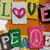 pixelated icons featuring letters, hearts, and peace symbols in green, pink, yellow, and white on an orange background