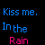 Pixelated text displays 'Kiss me. In the Rain' in blue and pink on black background with gray rectangle overlay.