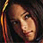 Pixelated close-up of a person's face with dark hair and light skin, set against a dark background with vertical orange-yellow stripes on the left.