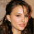 A static pixelated image shows a person with long dark hair, light skin, and a neutral expression against a plain background.
