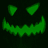 Green pixelated jack-o'-lantern face with triangular eyes and jagged mouth on dark background, displayed in a