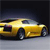 A yellow sports car with a sleek body and dark wheels is positioned on a light gray surface against a dark background.