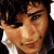 Two pixelated headshots of a young man with dark hair, one in color and one in grayscale, below which appears pink text reading 'tom welling' with a heart symbol.