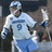 Pixelated image of a person in a light blue sports uniform with the number 9, wearing a helmet and holding a hockey stick, standing on an ice rink.