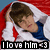 A person in a white jacket and blue shirt lies under a red blanket with hands behind their head, eyes closed, and a slight smile, with text overlay reading "I love him <3".
