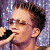 A pixelated image shows a person singing into a microphone on the left, with purple background and white text reading "chelsea and chris" on the right.