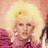 Pixelated static image of a person with blonde hair wearing pink clothing against a light background.