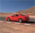 A red sports car is positioned on a sandy terrain with a clear blue sky in the background, captured in a static pixelated image.