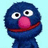 Blue puppet-like character with large white eyes, black pupils, pink nose, and red mouth on light blue background.