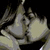 Pixelated static image of a light-colored abstract shape with dark background, possibly depicting a stylized kiss or embrace gesture.