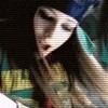 A static image of a person with long light brown hair wearing a blue headband and a green-and-yellow checkered shirt, resting their head on their hand.